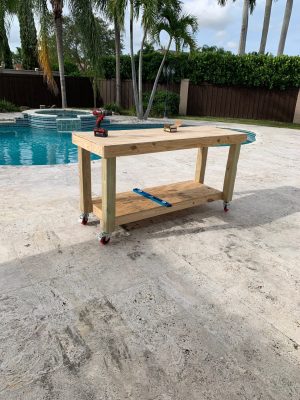 A wooden table with some tools on it near a pool.