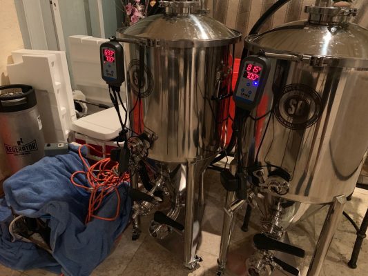 A home setup of two beer fermenters with electronics connected to it.